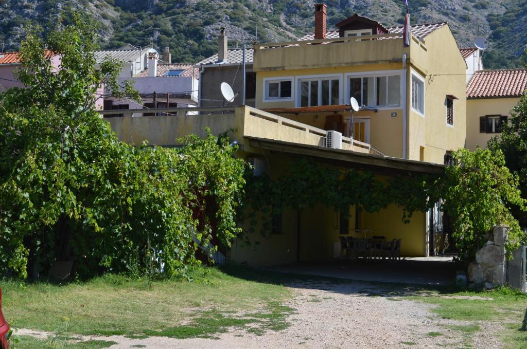 a yellow house with a balcony on top of it at Apartments Petar in Draga Bašćanska