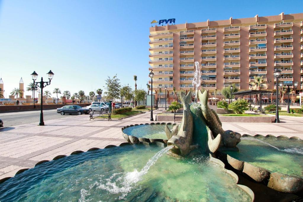 une fontaine en face d'un grand bâtiment dans l'établissement Apartment PYR, à Fuengirola