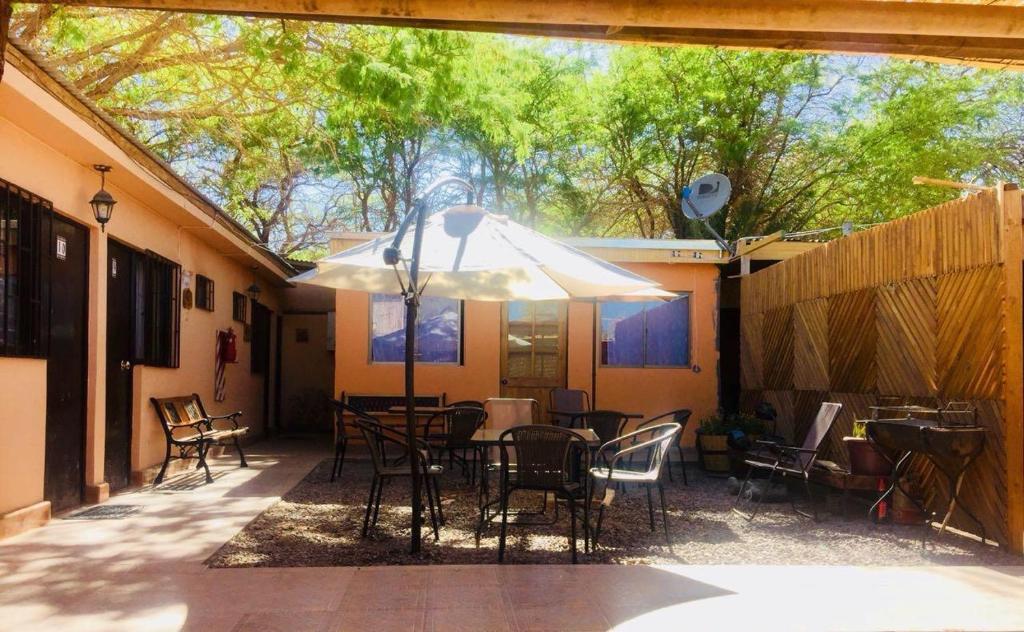 patio con tavolo, sedie e ombrellone di Hostal Intipara a San Pedro de Atacama