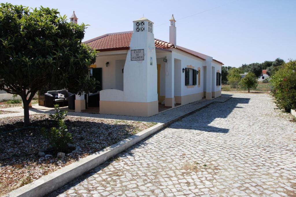 a building with a clock tower next to a road at Guest House Alfarrobeiras in Albufeira