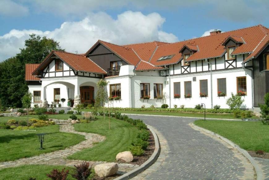 a large white house with a pathway in front of it at Dworek nad Regą in Trzebiatów
