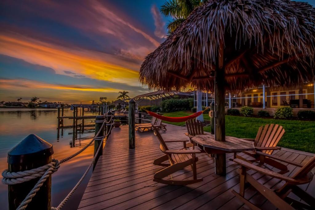 a wooden deck with chairs and a hammock and an umbrella at Villa Thunderbird View, Cape Coral in Cape Coral