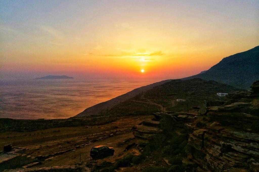 a sunset on a mountain with the sun setting over the ocean at Katerina's Sunset in Panormos