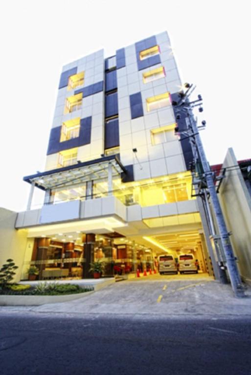 a large building with two cars parked in front of it at D'Kalpa Hotel Demangan Yogyakarta in Yogyakarta
