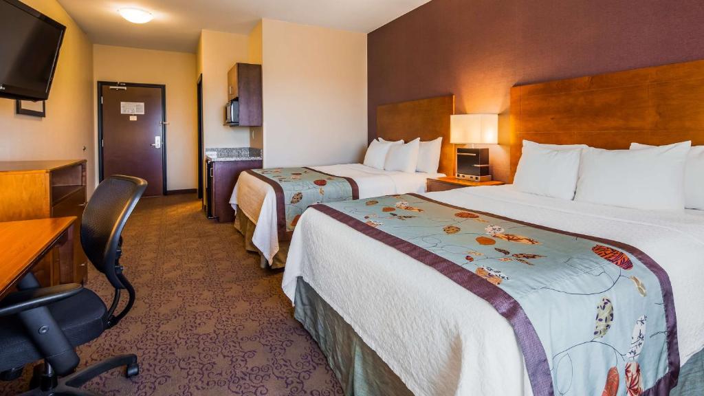 a hotel room with two beds and a desk at Best Western Plus Carousel Inn & Suites Burlington in Burlington