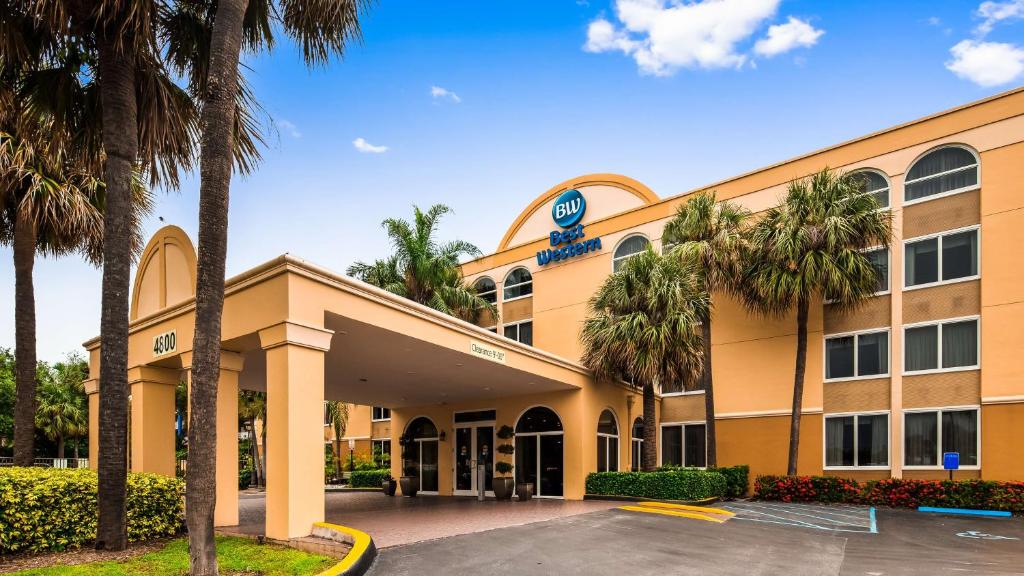 a hotel with palm trees in front of a building at Best Western Ft Lauderdale I-95 Inn in Fort Lauderdale