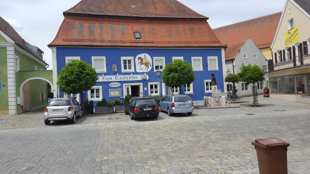 un edificio azul con coches estacionados frente a él en Pension "Zum Raubritter" en Langquaid