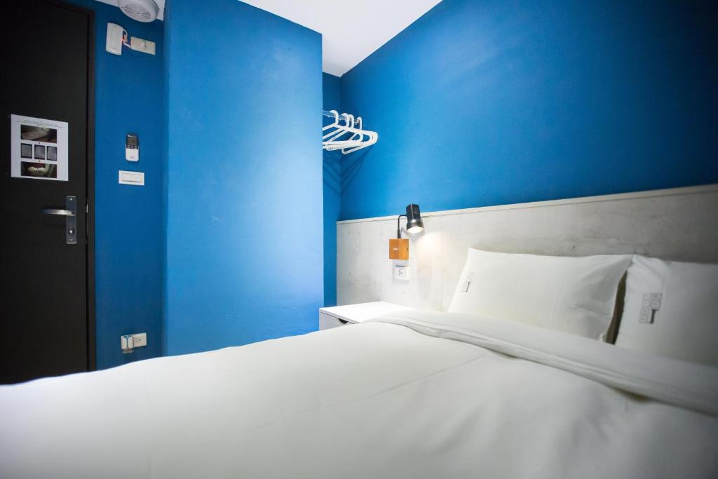 a bedroom with blue walls and a white bed at We Come Hostel in Taipei