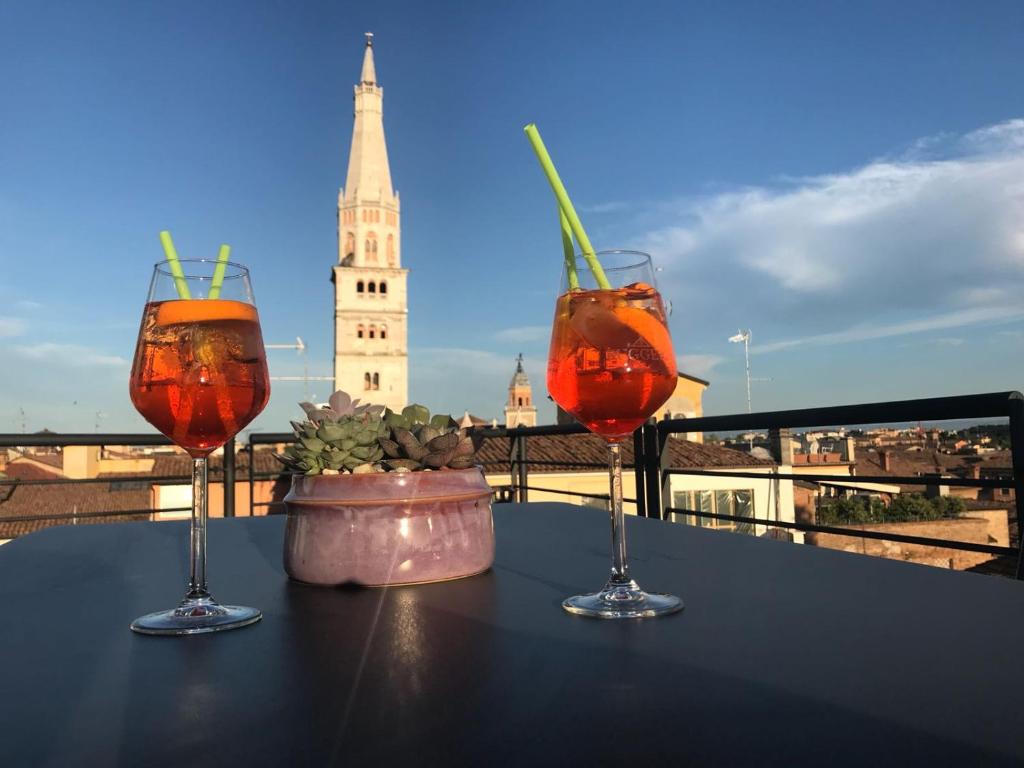 three drinks on a table with a view of a tower at Modena Charme in Modena