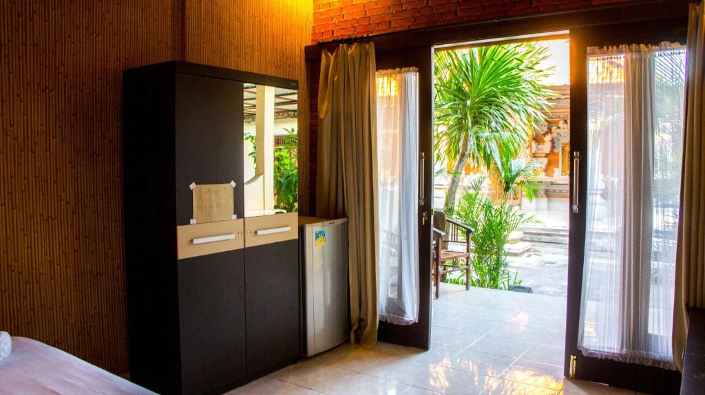 a room with a door open to a patio with a palm tree at Leyeh Leyeh Homestay in Canggu