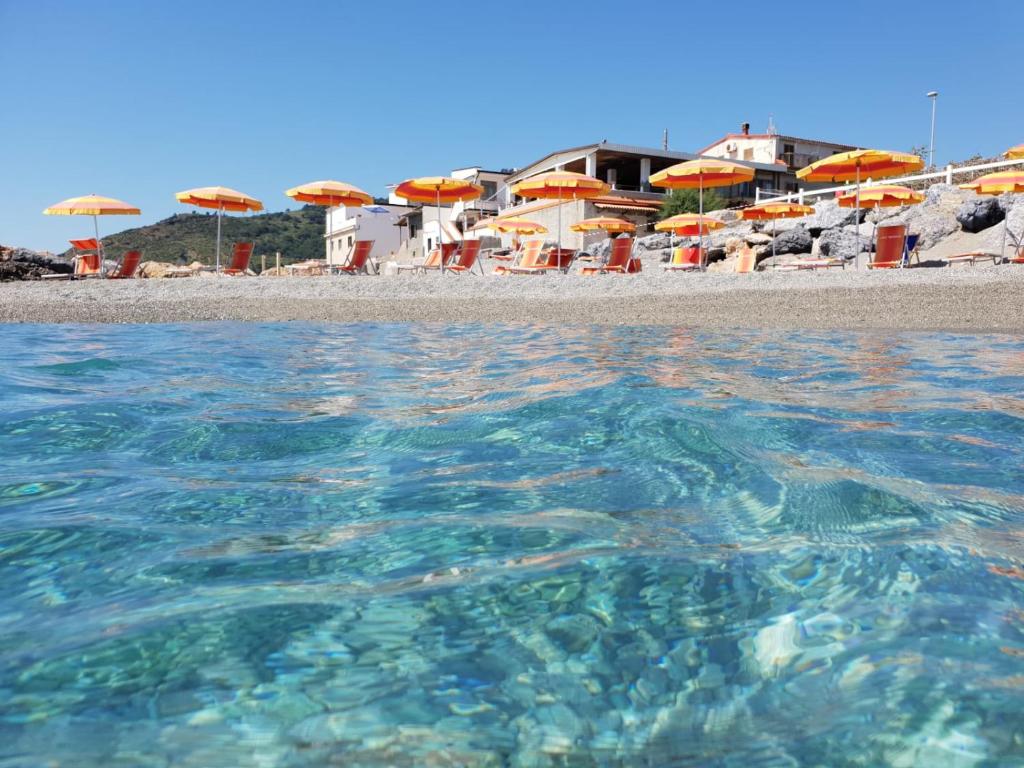 a beach with chairs and umbrellas and the water at Eremo sul Mare in Marina di Fuscaldo