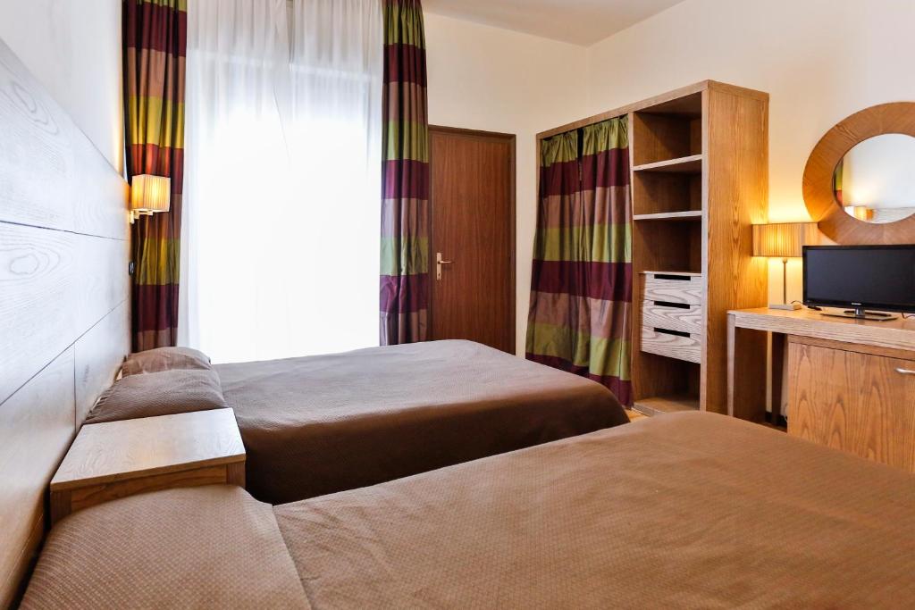 una camera d'albergo con due letti e una televisione di Hotel Avana Mare a Rimini