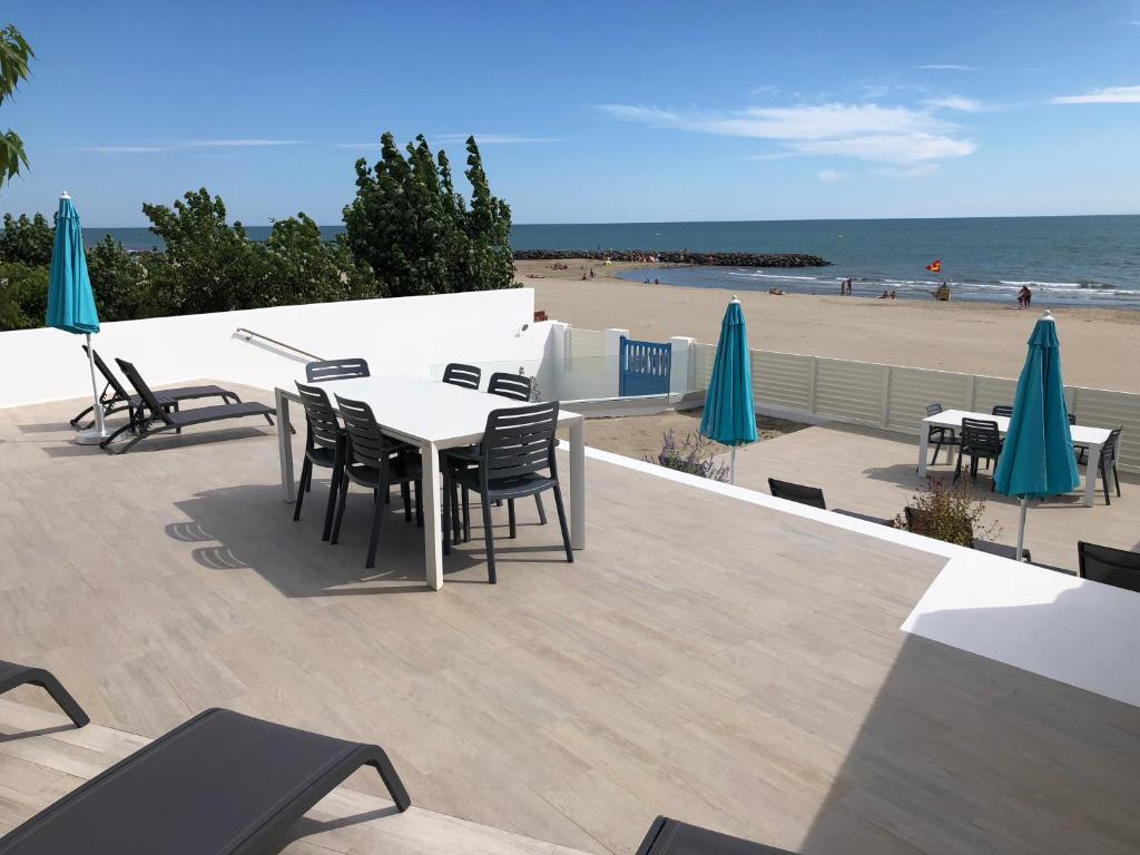 une terrasse avec une table et des chaises et la plage dans l'établissement La Vigie, au Grau-dʼAgde