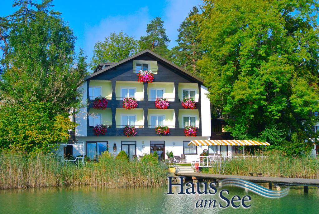 una casa con flores en los balcones sobre el agua en Haus am See en Sankt Kanzian