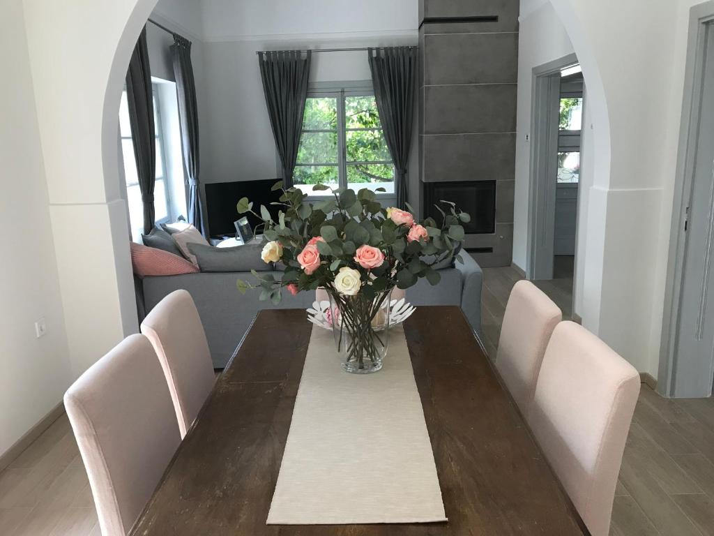 a dining room table with a vase of flowers on it at Dina's House in Spata
