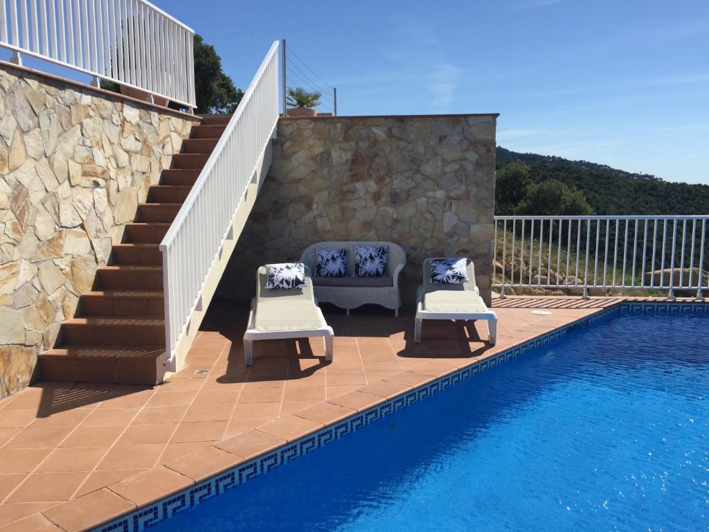 un patio con 2 sillas junto a una piscina en Villa Gardenia mit Pool und traumhaftem Meerblick, en Santa Cristina d'Aro