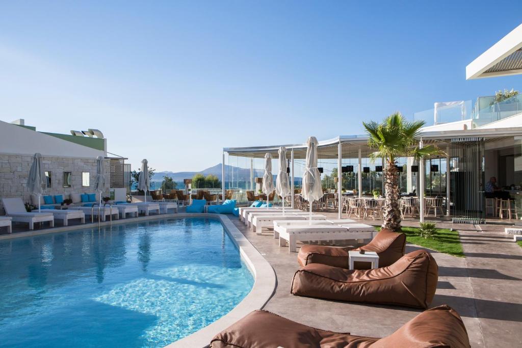 a pool with chaise lounges and chairs next to a resort at Aloe Boutique Hotel & Suites - adults only in Almyrida