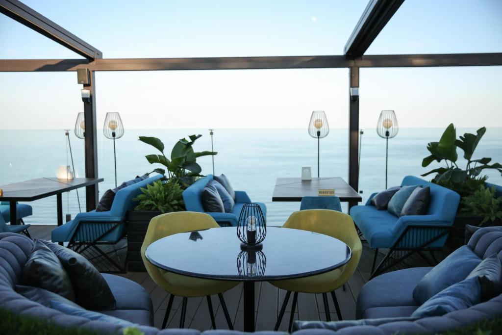 um pátio com cadeiras e mesas e vista para o oceano em Kolyada Hotel em Odessa