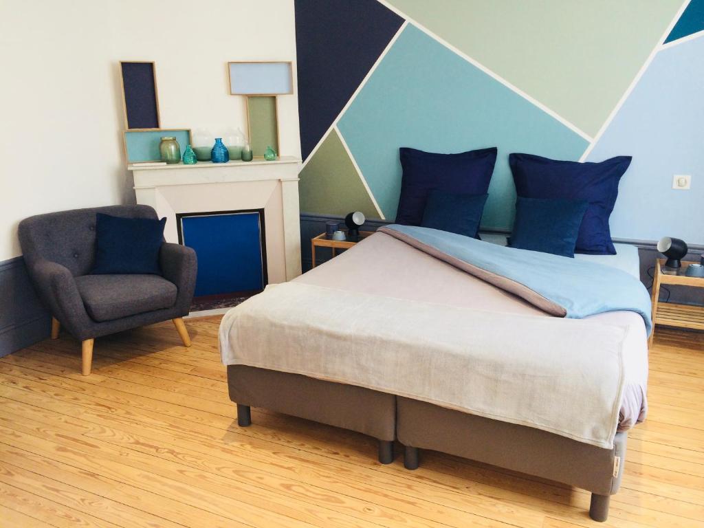 1 dormitorio con 1 cama y 1 silla en Chambres d'hotes Les Nuits Pastel en Saint-Quentin