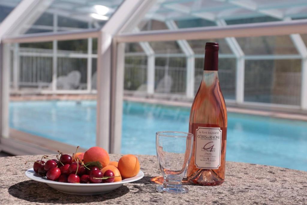 - une bouteille de vin à côté d'une assiette de fruits et d'un verre dans l'établissement Les Grands Prés des Baronnies, à La Roche-sur-le-Buis