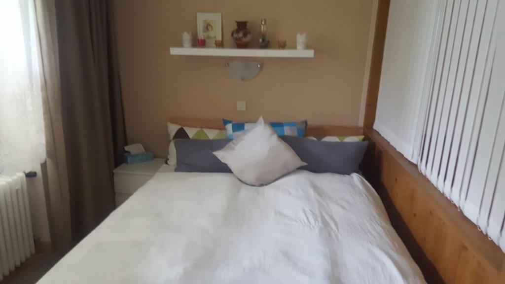 - un lit avec des draps blancs et des oreillers bleus à côté d'une fenêtre dans l'établissement Alpina Inzell 335 Chiemgaukarte, à Inzell
