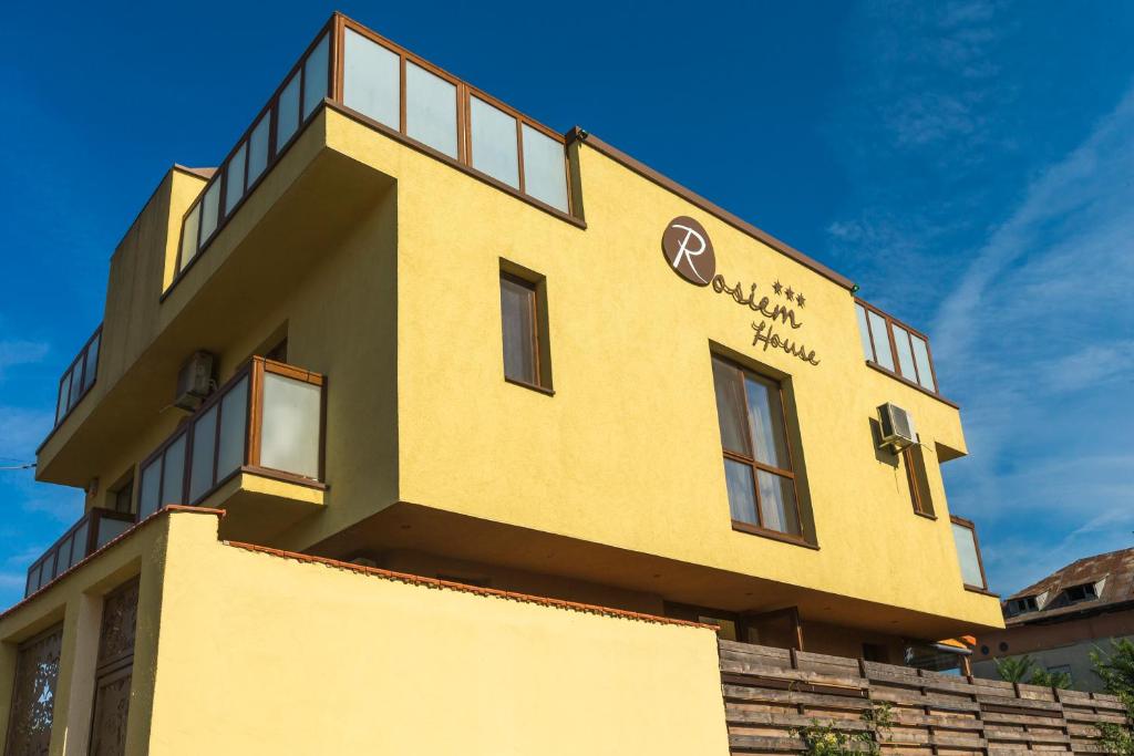 een geel gebouw met een bord aan de zijkant bij Rosiem House in Techirghiol