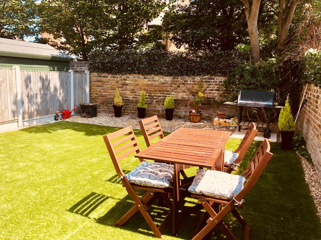 a wooden table and two chairs in a yard at Garden Oasis in Margate