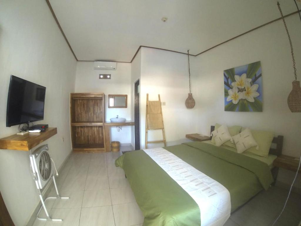 a bedroom with a green bed and a flat screen tv at Cape Rose in Gili Trawangan