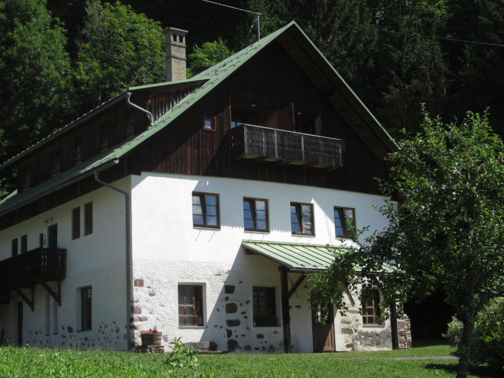 ein großes weißes Haus mit Holzdach in der Unterkunft Schloss Manndorf Gästehaus in Kötschach