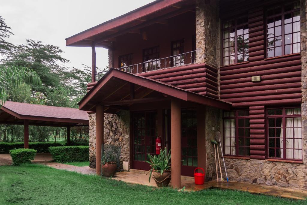 a wooden house with a balcony and a yard at Oilepo Cottage in Naivasha