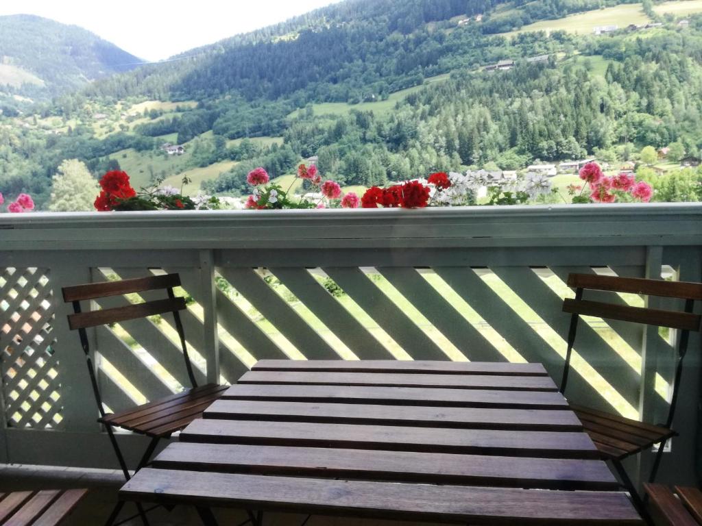 um banco de madeira sentado numa varanda com flores em Pension Julia em Feld am See