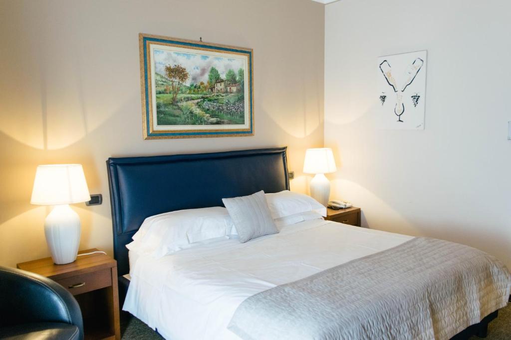 una camera da letto con un letto con lenzuola bianche e due lampade di Villa San Carlo a Cortemilia