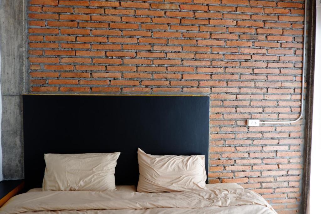 a brick wall with a bed in front of it at Black Elephant Boutique in Suratthani