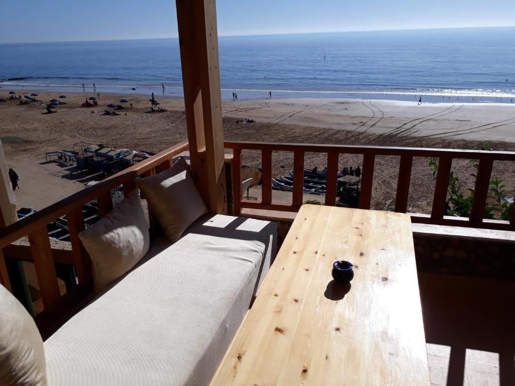 una mesa de madera en un balcón con vistas a la playa en Playa Surf House, en Taghazout