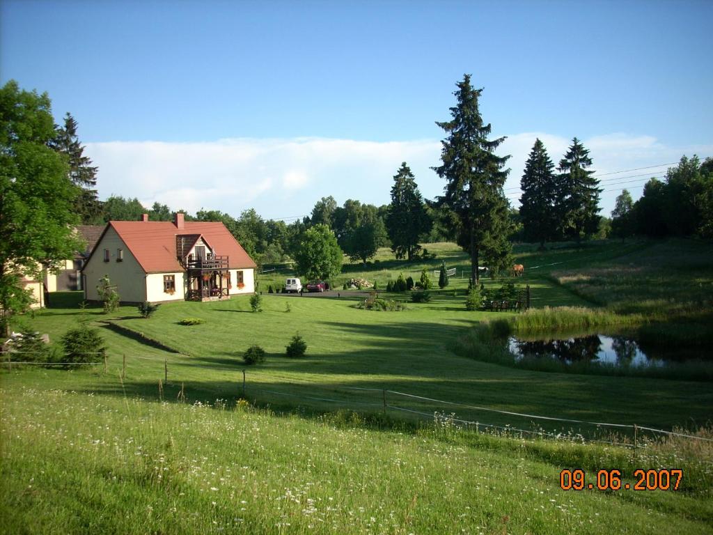 a house in the middle of a field with a pond at Agroturystyka Dolinka in Szczecinek