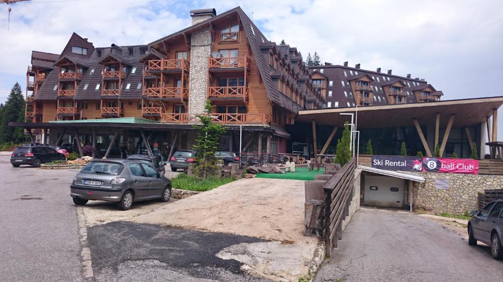 a large building with cars parked in front of it at Apartman aparthotel Vučko in Jahorina