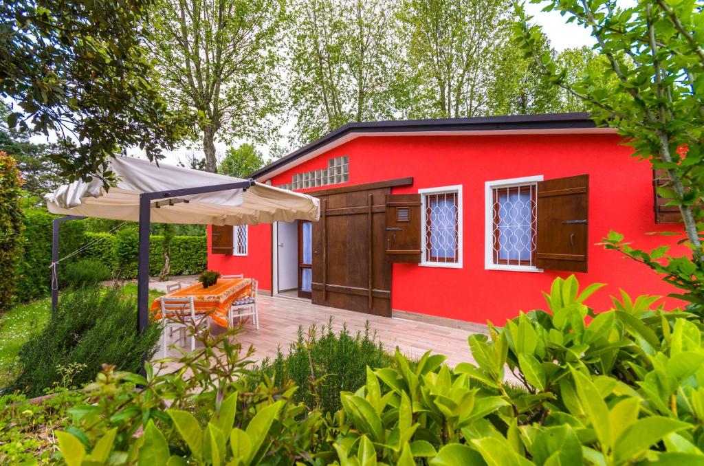 a red house with a patio and an umbrella at Villa Bouganville in Bibione