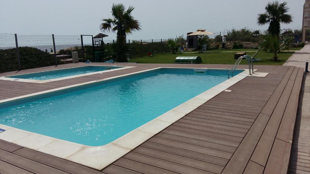 una piscina con terraza de madera junto a un edificio en appart luxueux pieds dans l'eau en Port El Kantaoui