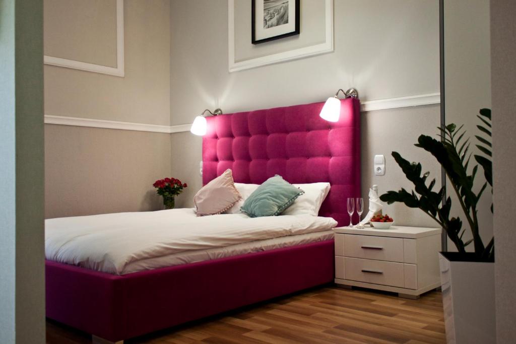 1 cama con cabecero rosa en una habitación en Aparthotel Przy Plaży, en Międzyzdroje