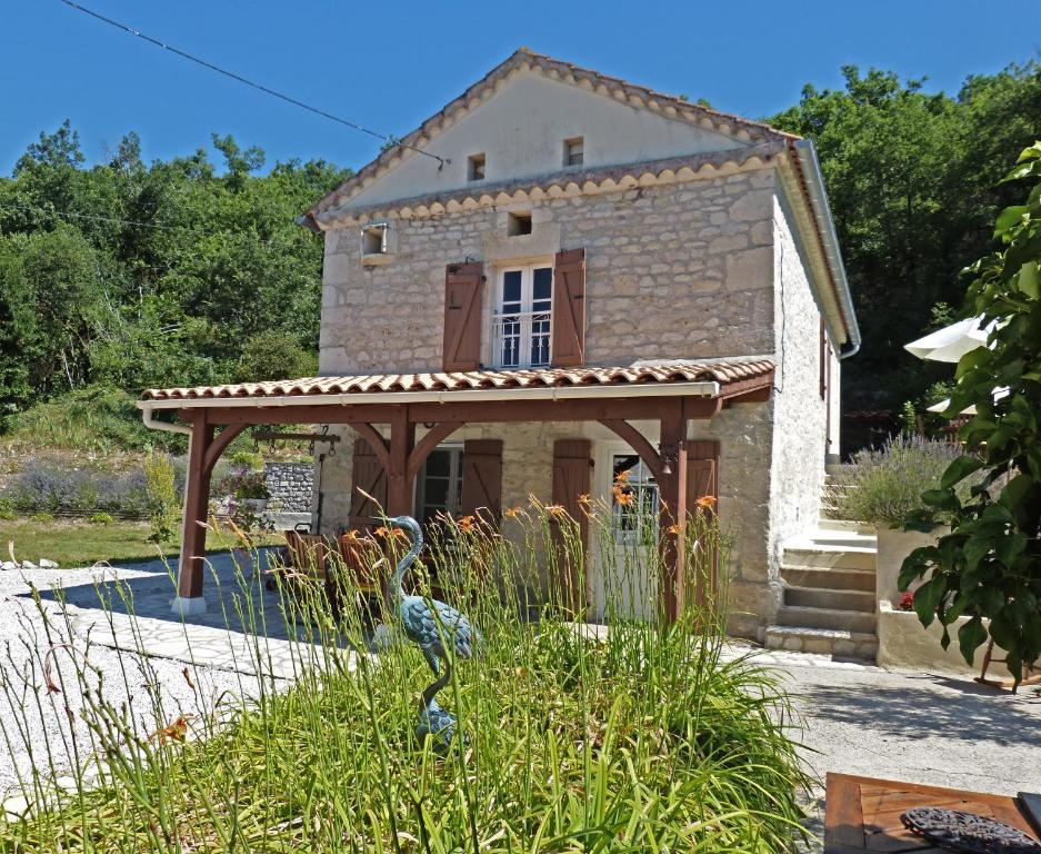 a small stone house with a pergola in a garden at d'Est en Ouest in Montcuq