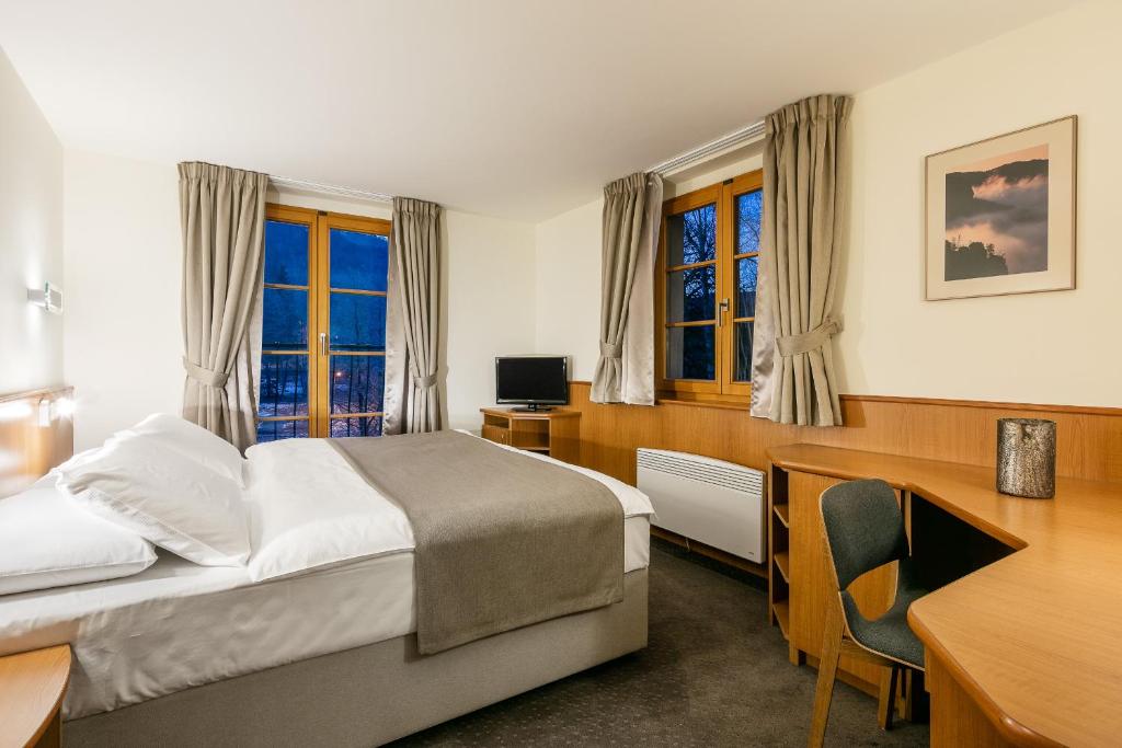 a hotel room with a bed and a desk and a desk at Hotel Ostrov in Tisá
