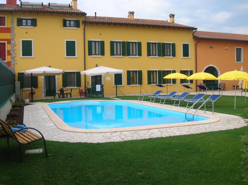 una piscina con sedie e ombrelloni di fronte a un edificio di Agriturismo Colombarola a Sona