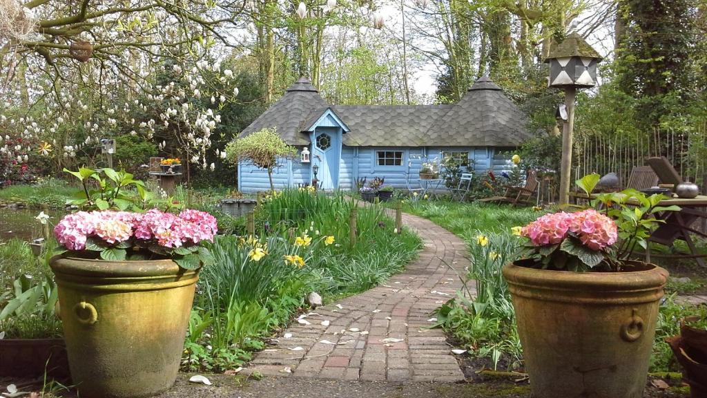 a garden with a small blue house with flowers in front at Pieni Talo in Bakhuizen