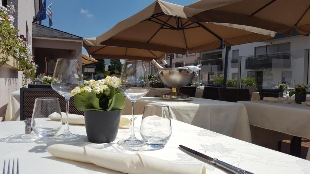 a table with glasses and a vase of flowers on it at Hotel Re'ser Stuff in Roeser