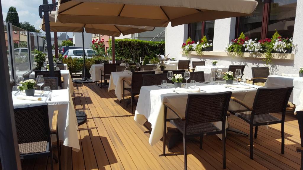 a restaurant with white tables and chairs and umbrellas at Hotel Re'ser Stuff in Roeser