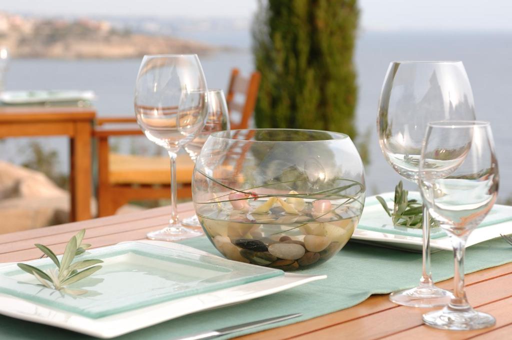 a table with three wine glasses and a bowl of rocks at Thalassa Boutique Hotel & Spa in Coral Bay