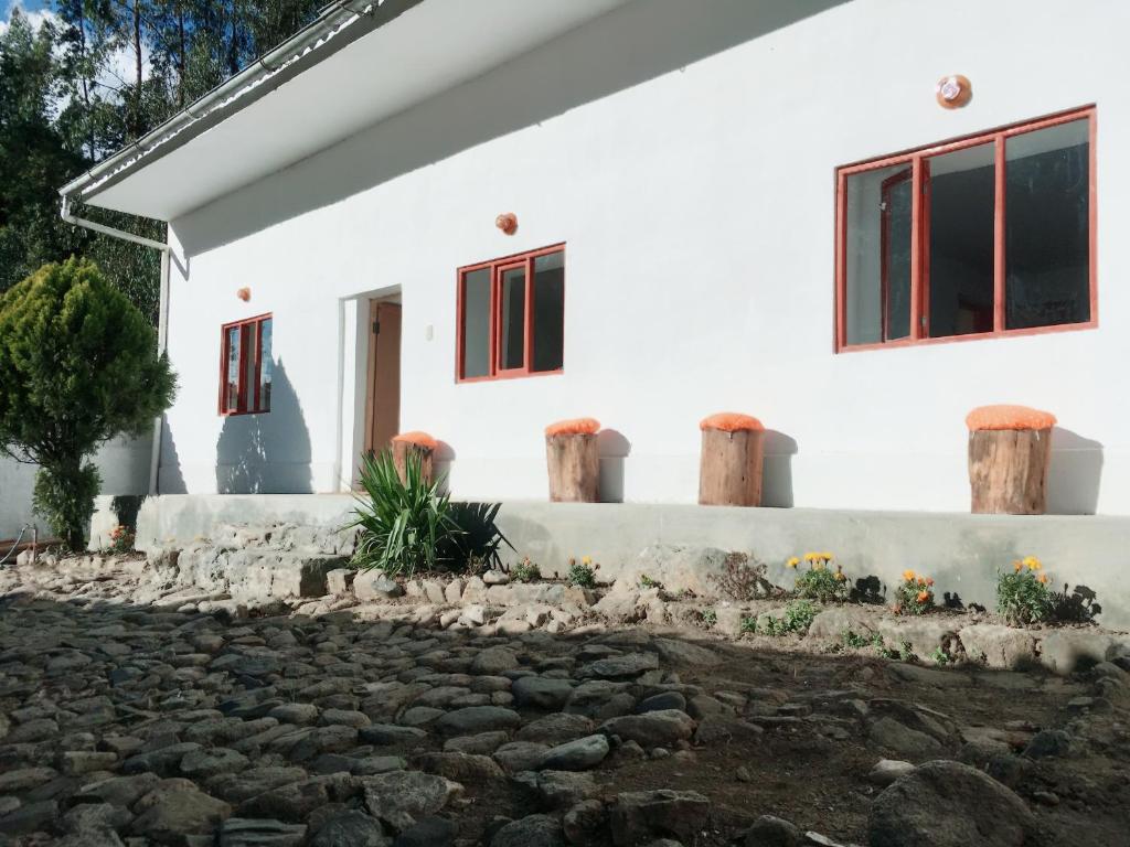 Casa I Love Huaraz في هواراس: منزل أبيض بنوافذ حمراء وممر حجري