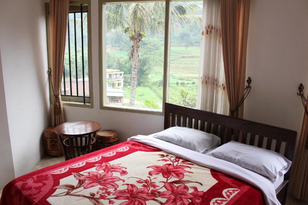 ein Schlafzimmer mit einem Bett und einem Fenster mit einem Baum in der Unterkunft Villa KenDedes Garden in Batu