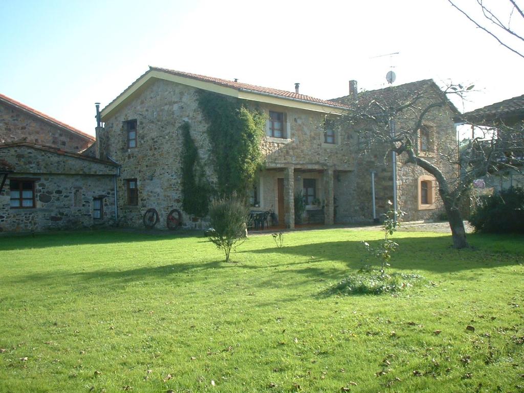 uma grande casa de pedra com um quintal verde em La Llosa em Villaviciosa