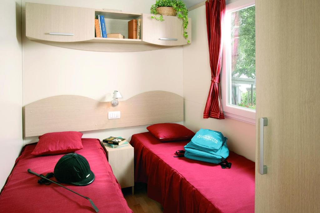 two beds in a small room with red and blue at New Camping Le Tamerici in Marina di Cecina